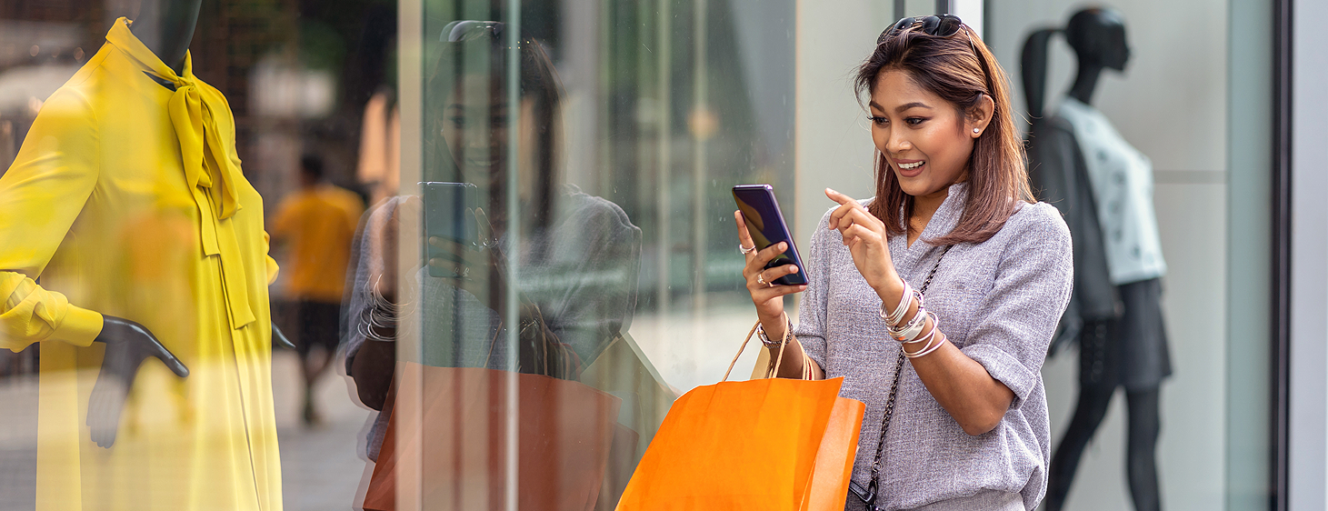 Frau mit dem Handy und einer Shoppingbag